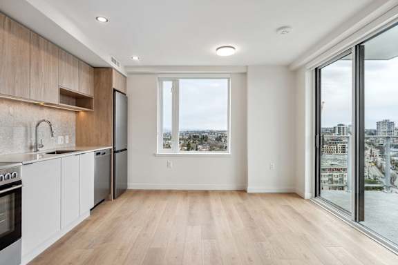 A kitchen with wooden floors and a view of the city through a window.