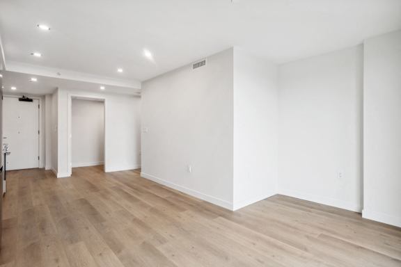 A large empty room with wooden flooring and white walls.