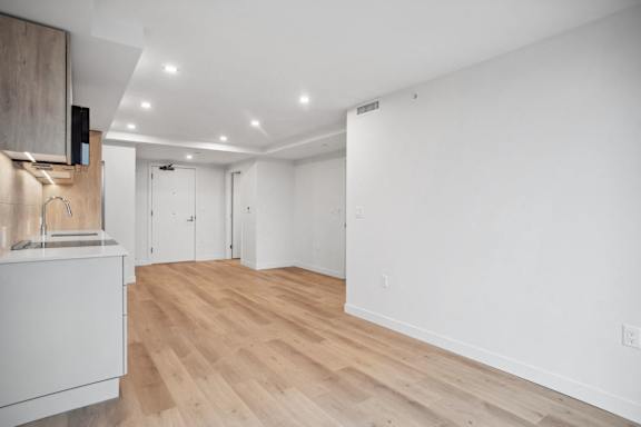 A kitchen with white cabinets and a wooden floor.