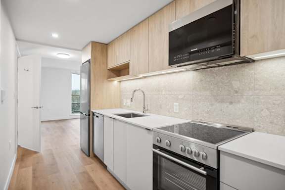 A modern kitchen with a stainless steel oven and white cabinets.