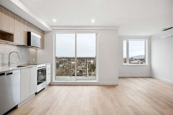 A modern kitchen with wooden floors and white appliances.