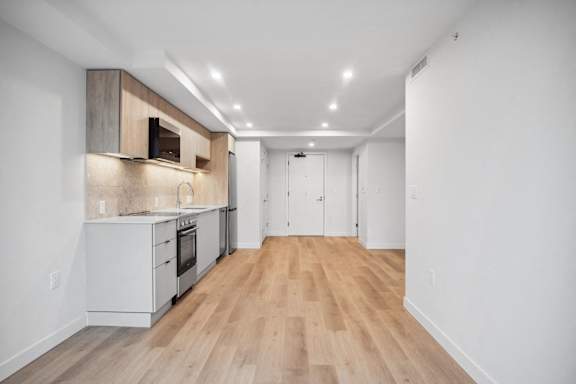 A kitchen with white cabinets and a wooden floor.