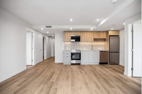 A modern kitchen with wooden floors and white walls.