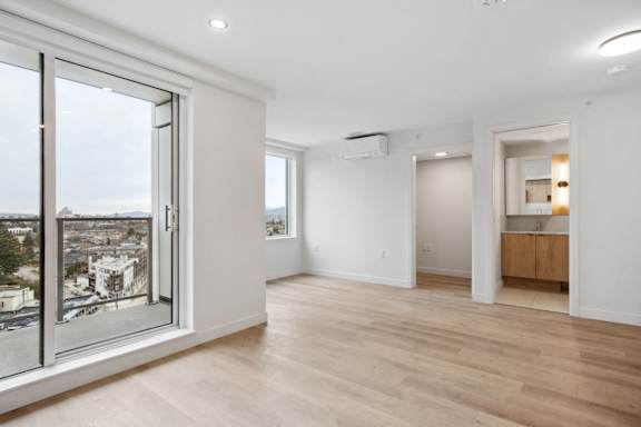 A spacious room with wooden floors and a view of the city through a large window.