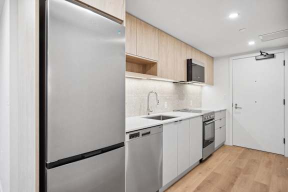 A modern kitchen with a refrigerator, sink, and cabinets.