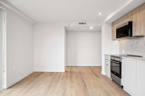 A kitchen with white cabinets and a wooden floor.