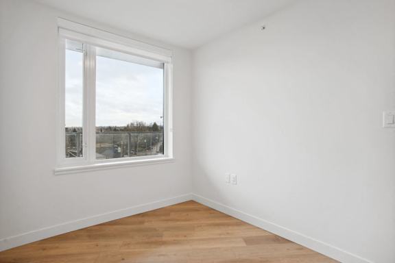 A room with a window and wooden flooring.