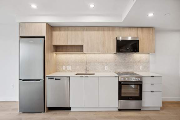 A modern kitchen with a refrigerator, dishwasher, oven, and microwave.