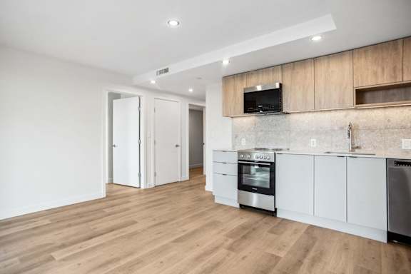 A modern kitchen with wooden floors and stainless steel appliances.