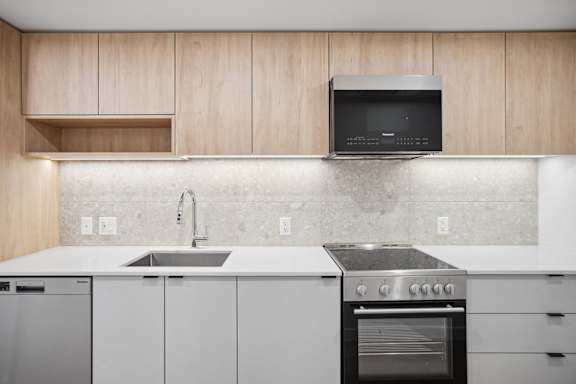 A modern kitchen with a stainless steel oven and a microwave above the sink.