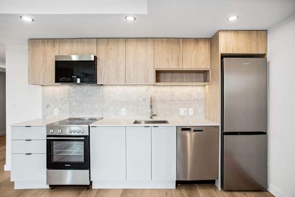 A modern kitchen with a stainless steel refrigerator and oven.