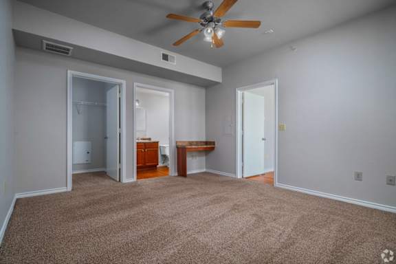 A room with a ceiling fan and carpeted floor.