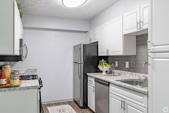 A kitchen with white cabinets and a black refrigerator.