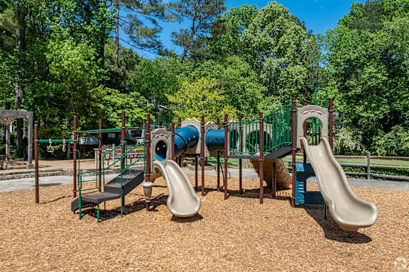 A playground with a slide, swings, and a seesaw.