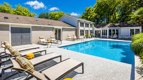 A poolside area with sun loungers and a building in the background.