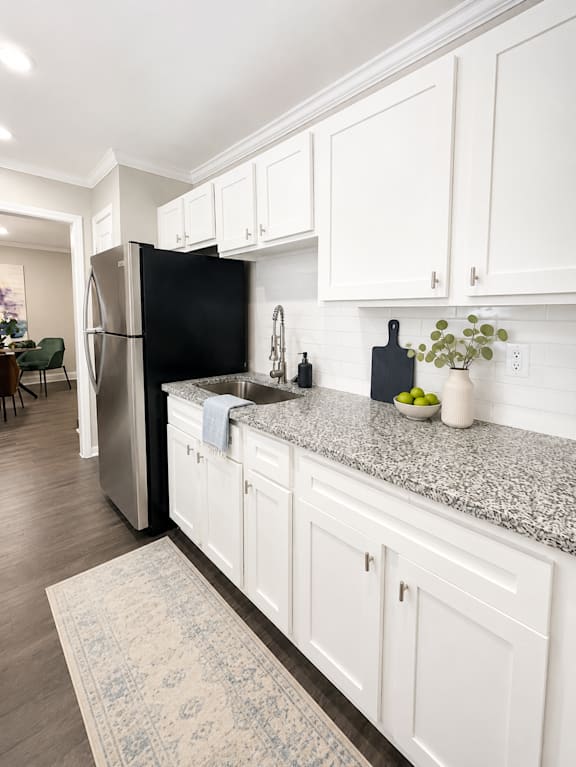A kitchen with white cabinets and a black fridge.