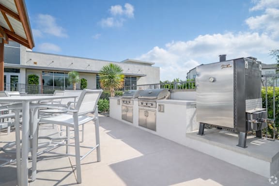 A patio with a table and chairs and a grill.