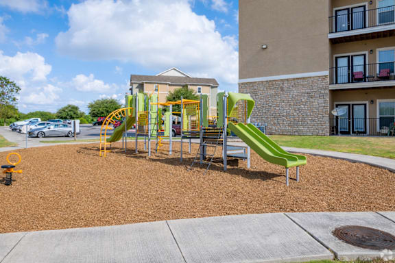 A playground with a green slide and a yellow and green play structure.