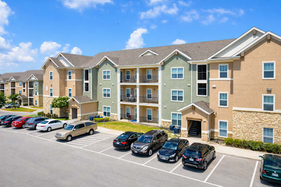 A parking lot in front of a multi-story apartment building.
