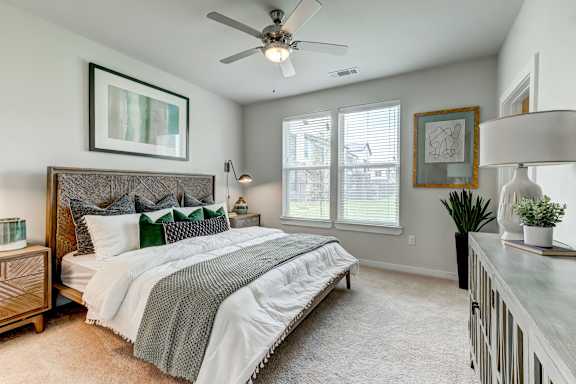 A bedroom with a large bed and a ceiling fan.