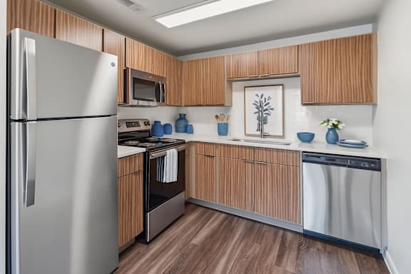 A kitchen with wooden cabinets and a stainless steel refrigerator.