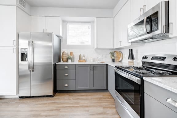 A modern kitchen with a stainless steel refrigerator, microwave, and oven.