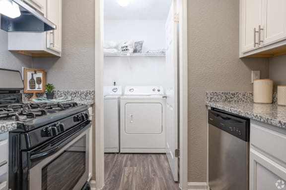 A kitchen with a black stove top oven and a white dishwasher.