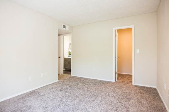 A spacious room with carpeted floor and two doors.