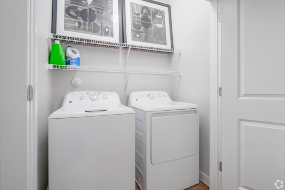 Two white washing machines in a small laundry room.