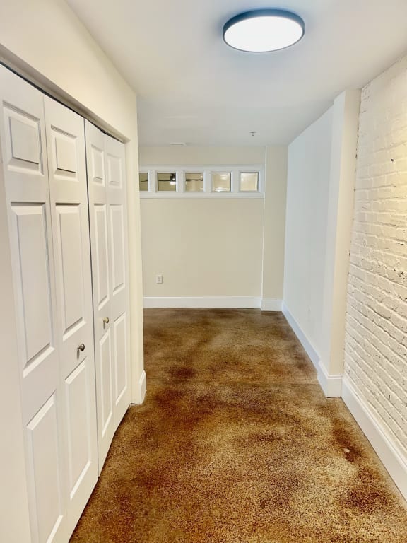 an empty room with white closet doors and a white brick wall