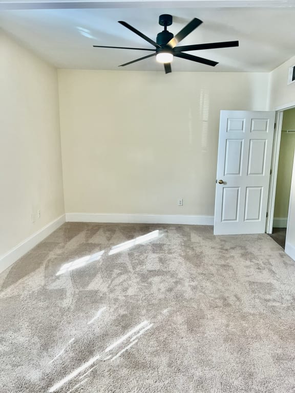 an empty room with carpet and a ceiling fan
