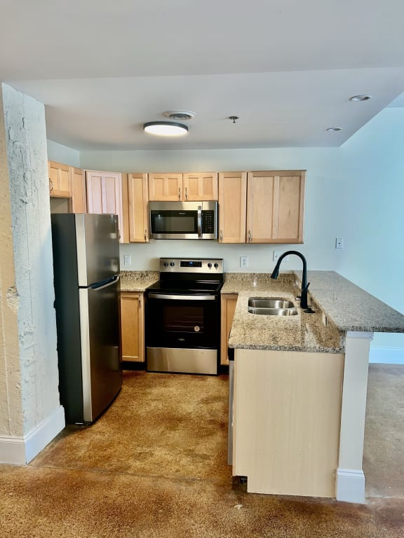 an empty kitchen with stainless steel appliances and granite counter tops