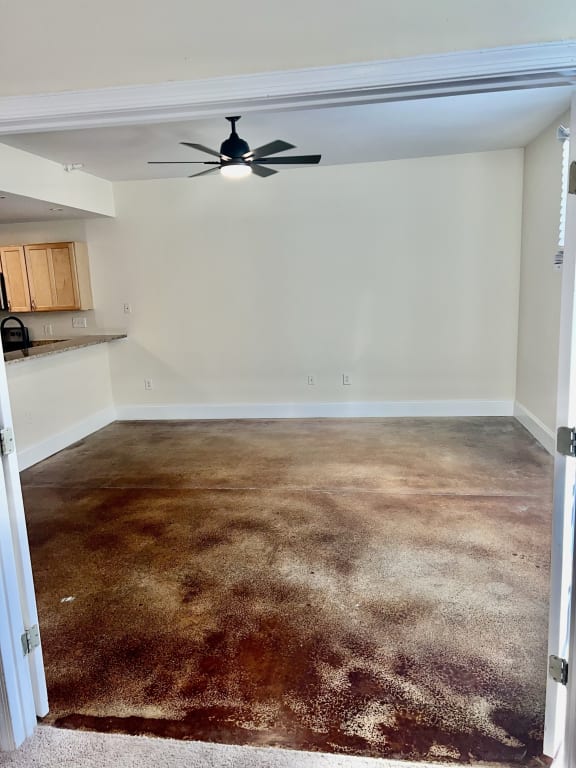 an empty living room with a ceiling fan and a carpeted floor