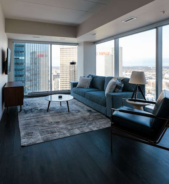 A living room with a couch, chair, and a table with a lamp on it.