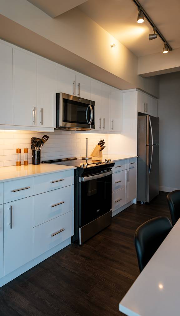 A modern kitchen with white cabinets and black appliances.