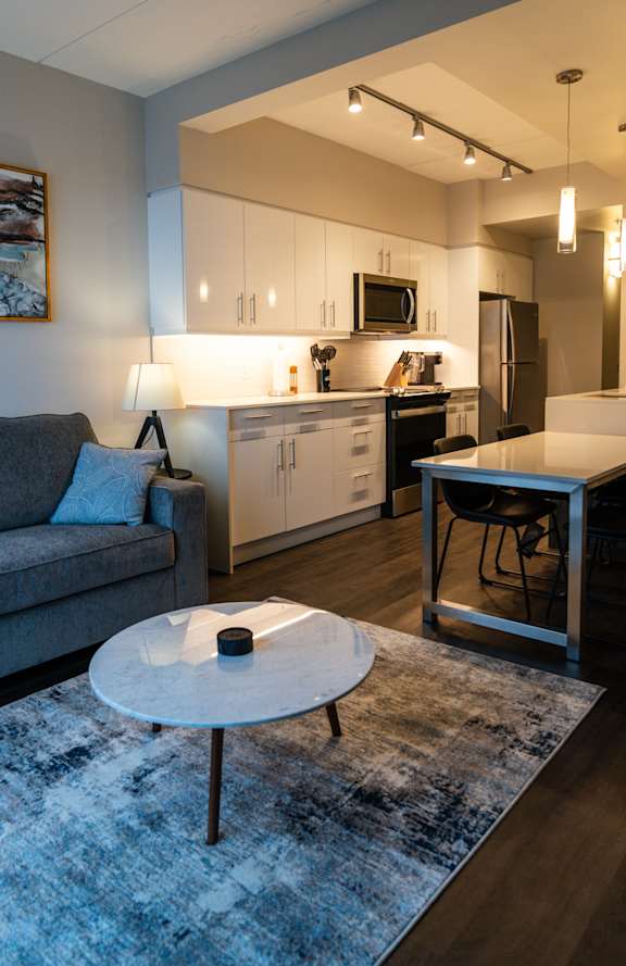 A modern living room with a grey couch and a round white table.