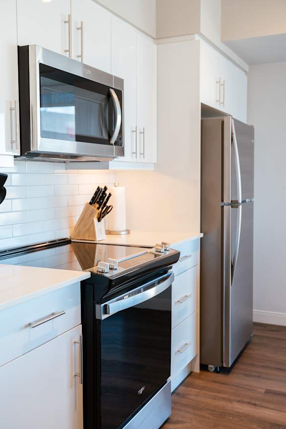 A modern kitchen with a black oven and white cabinets.