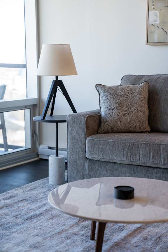 A lamp with a white shade is on a black tripod stand.