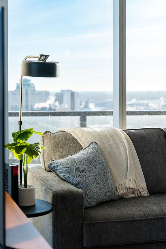 A grey couch with a pillow and a blanket on it.