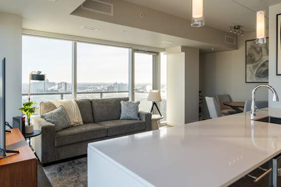A modern living room with a grey couch and a white table.