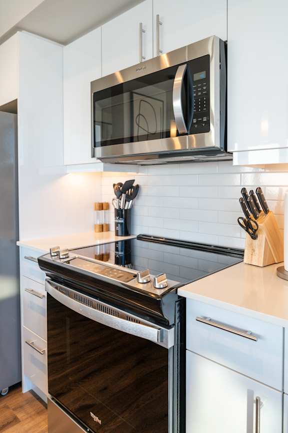 A modern kitchen with a stainless steel oven and microwave above a white counter.