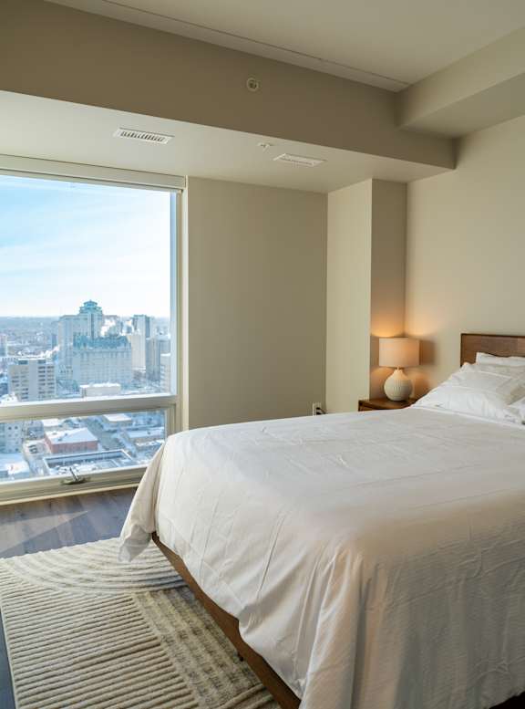 A bedroom with a large bed and a view of the city.