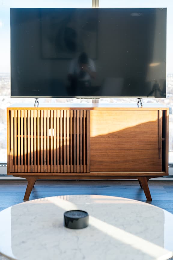 A wooden cabinet with slats is in front of a television.