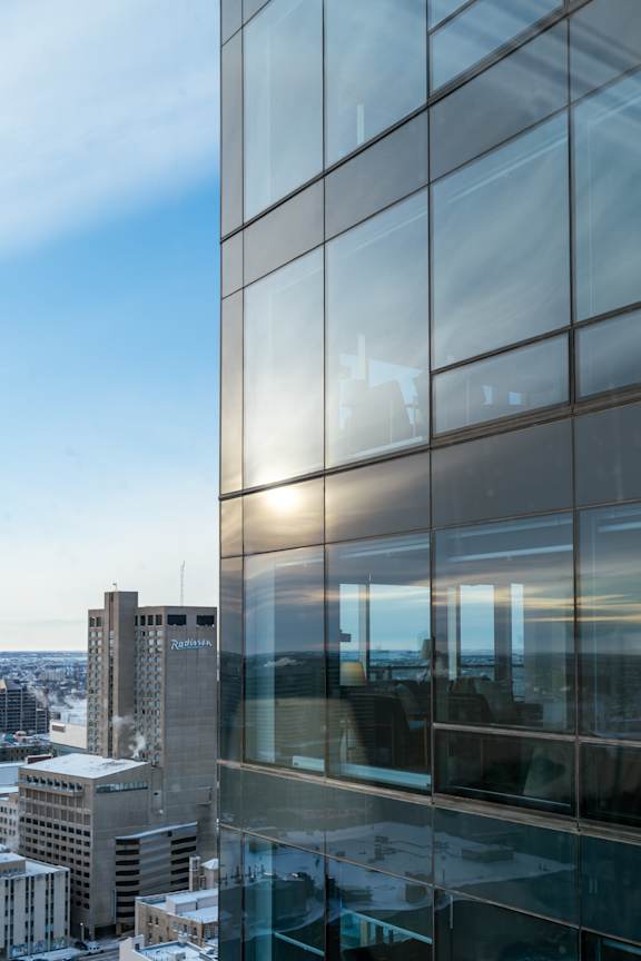 A tall glass building with a view of the cityscape in the background.