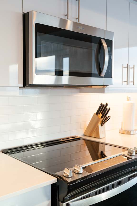 A modern kitchen with a stainless steel microwave above a stove.