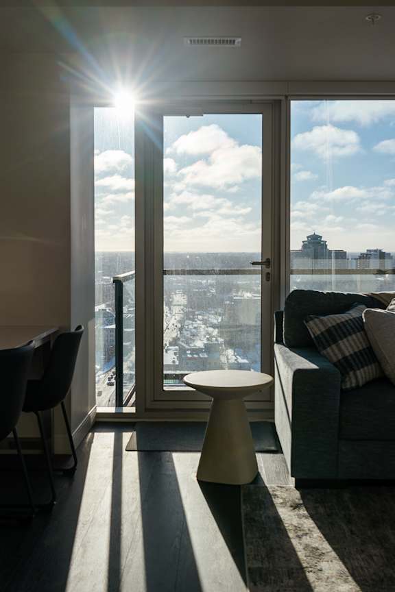 A sunny day is seen through a large window in a modern living room.