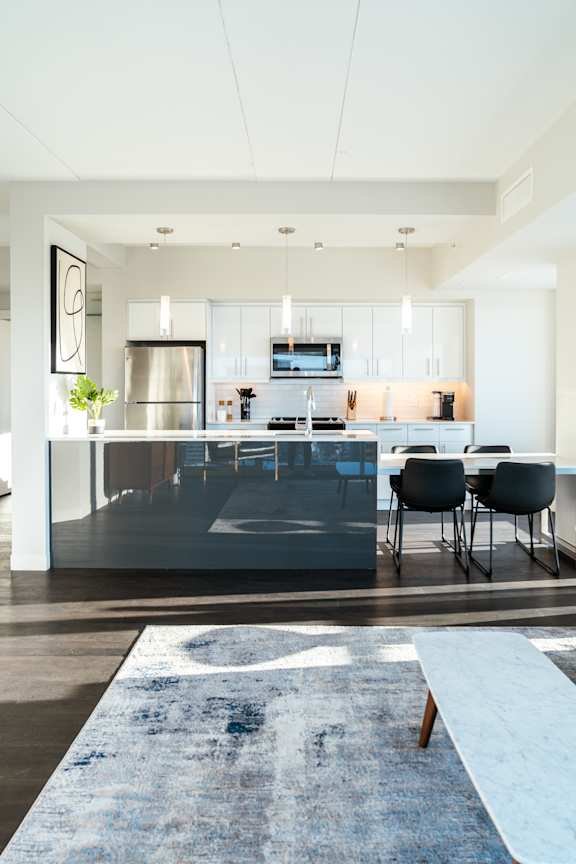 A modern kitchen with a large island and chairs.