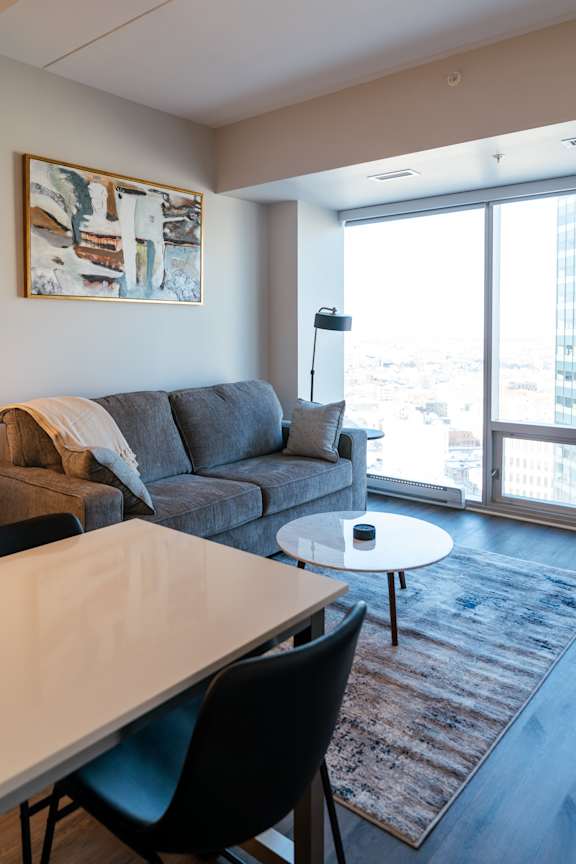 A living room with a grey couch and a white table.