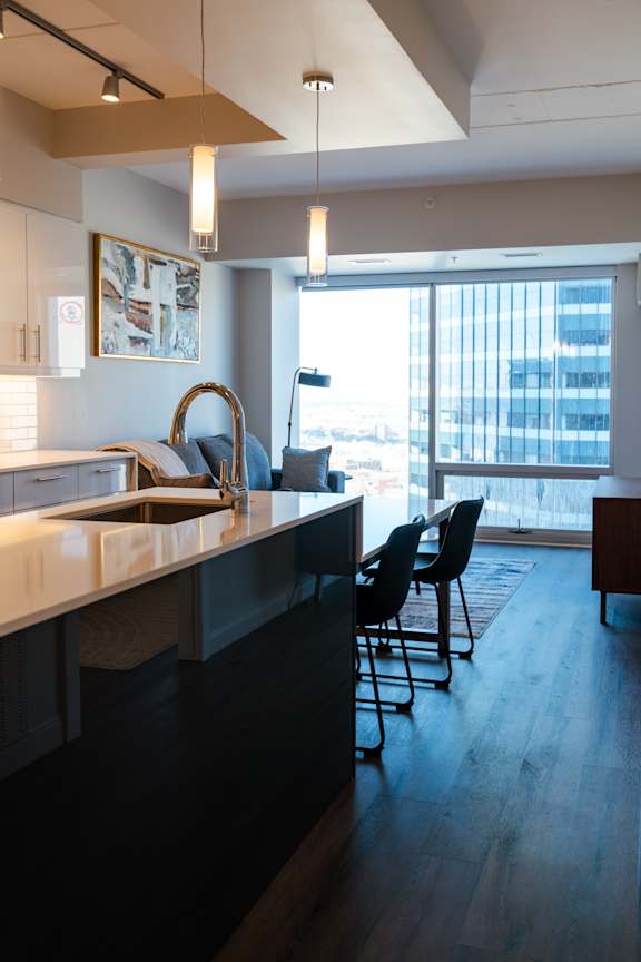 A modern kitchen with a large island and chairs.