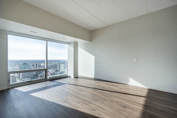 A large empty room with a view of the cityscape outside the window.